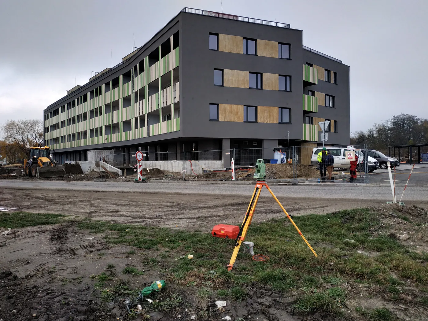 Totálna stanica na statíve pred novostavbou bytového domu